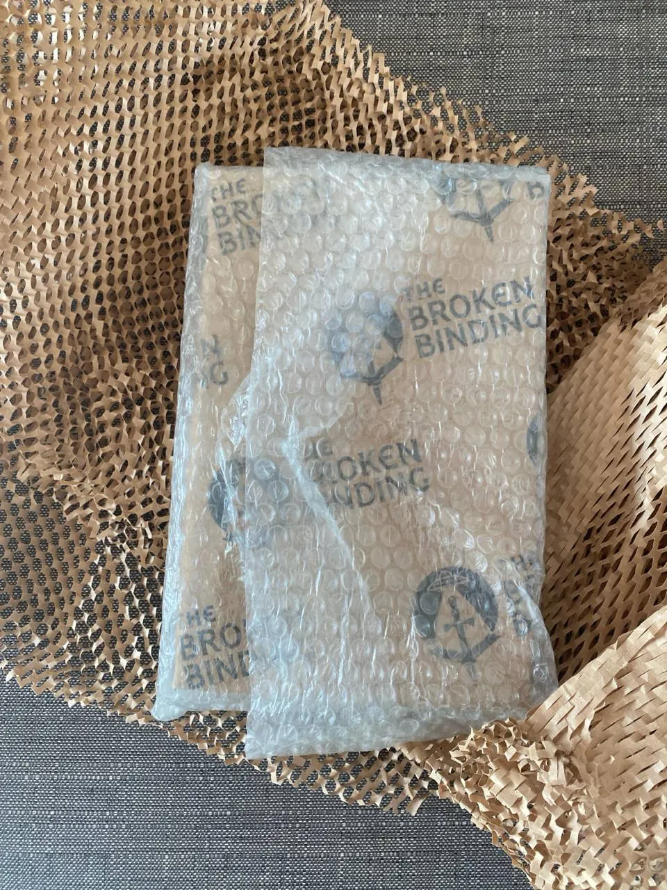 book wrapped in bubble wrap with 'The Broken Binding' logo