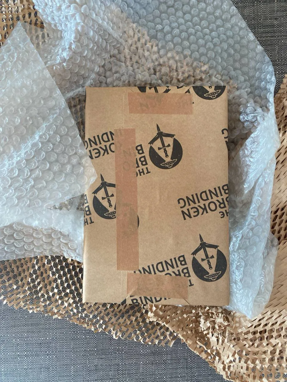 book wrapped in kraft paper with 'The Broken Binding' stamp